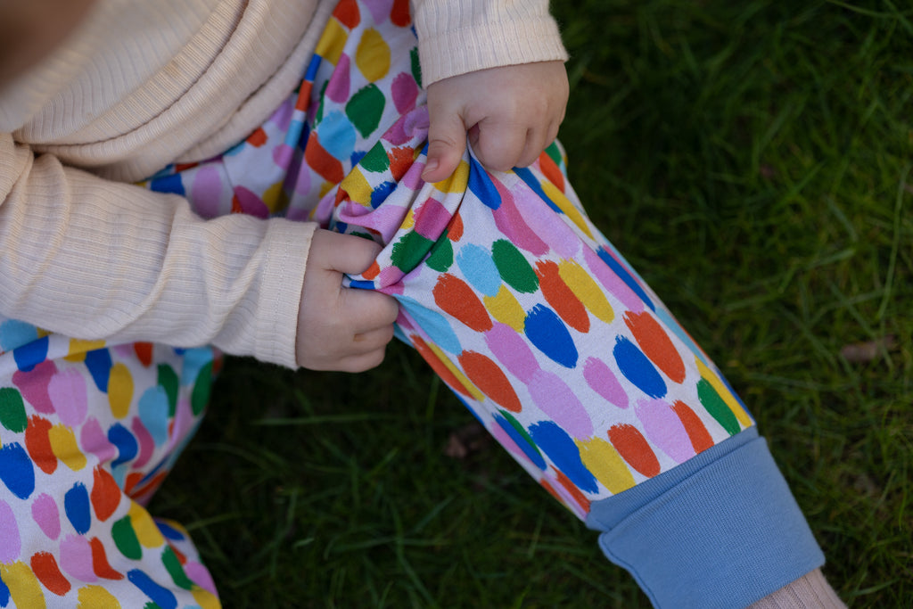 Paintbrush spot leggings worn by a child on grass
